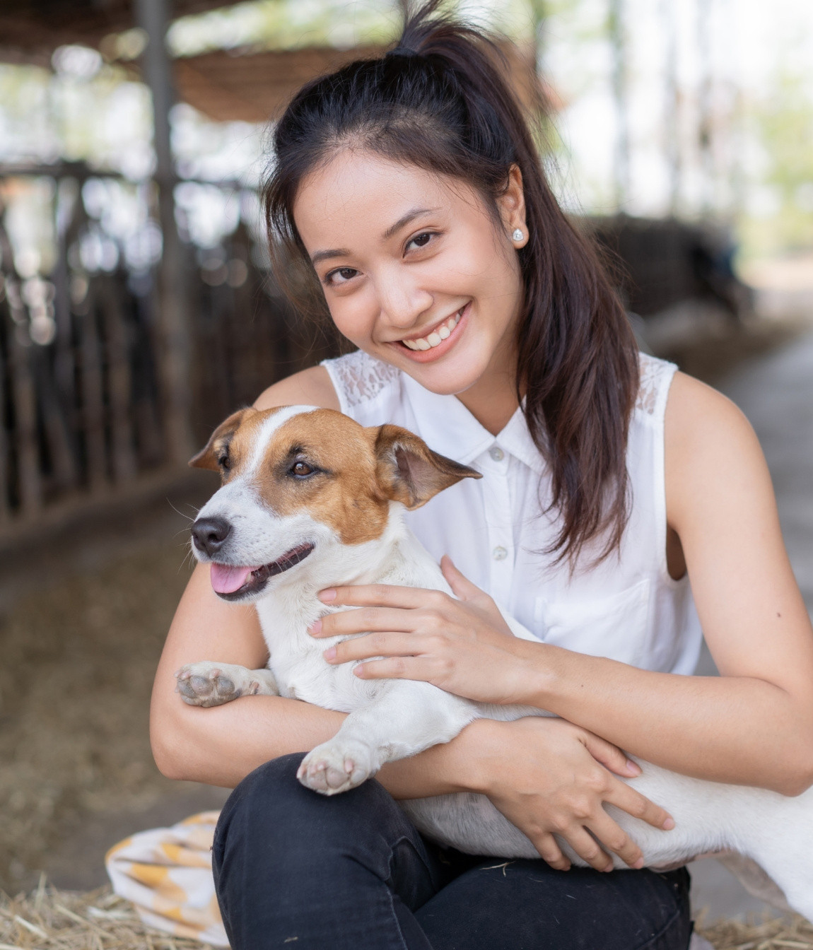 Young woman holding a dog on a farm